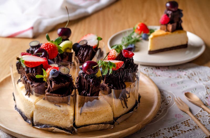 Bolo de queijo de brownie caseiro em chapa branca, decorado com morangos,  mirtilo e cereja, no jogo americano estilo inglês, na mesa de madeira.  usado para decorar a loja.