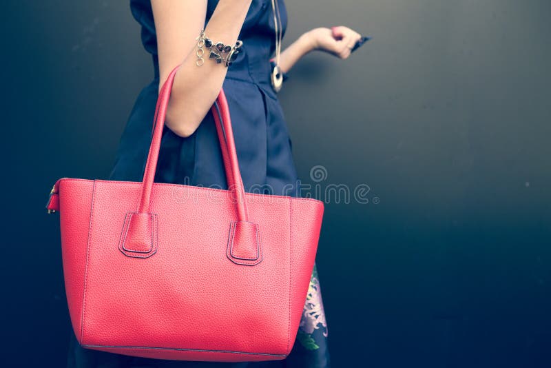 Bolsa vermelha grande bonita elegante no braço da menina em um vestido preto elegante, levantando perto da parede em um verão mor fotografia de stock Bolsa vermelha grande bonita elegante no braço da menina em um vestido preto elegante, levantando perto da parede em um verão mor fotografia de stock