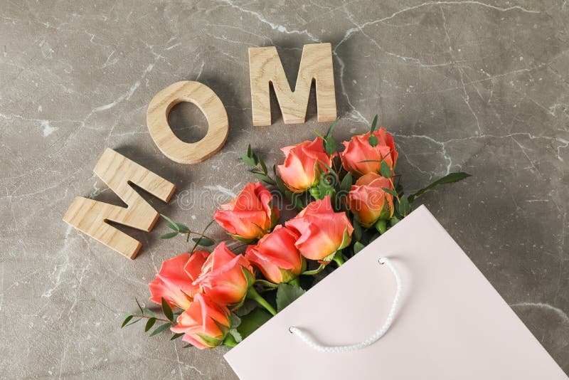 Bolso del regalo con el ramo de rosas y de mamá anaranjadas de la inscripción en fondo marrón fotos de archivo Bolso del regalo con el ramo de rosas y de mamá anaranjadas de la inscripción en fondo marrón fotos de archivo