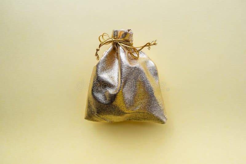 Bolso del regalo de la tela de oro en un fondo amarillo El concepto del d?a de fiesta fotos de archivo Bolso del regalo de la tela de oro en un fondo amarillo El concepto del d?a de fiesta fotos de archivo
