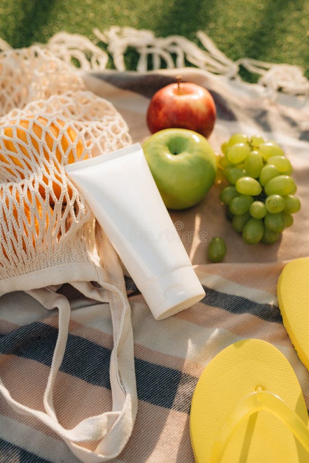 Bolso neto con chancleta, crema de la fruta del sol en la tela escocesa foto de archivo libre de regalías Bolso neto con chancleta, crema de la fruta del sol en la tela escocesa foto de archivo libre de regalías