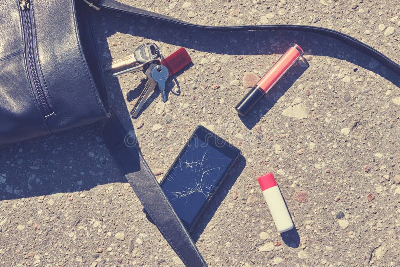 Bolso, teléfono roto, llaves y lápiz labial en la calle del asfalto imagen de archivo libre de regalías Bolso, teléfono roto, llaves y lápiz labial en la calle del asfalto imagen de archivo libre de regalías