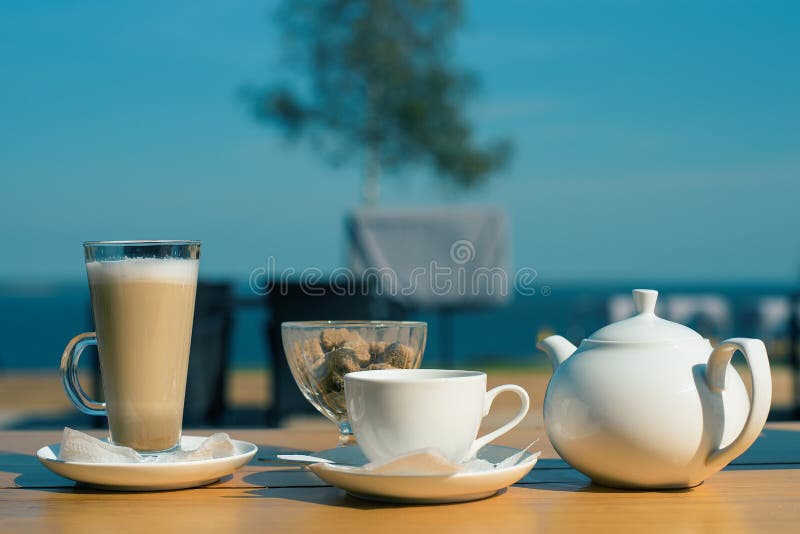 Bom Dia Ajuste Das Canecas Do Latte, De Um Copo Do Chá E De Um Bule Com  Açúcar De Bastão No Terraço Do Verão Do Café Imagem de Stock - Imagem de