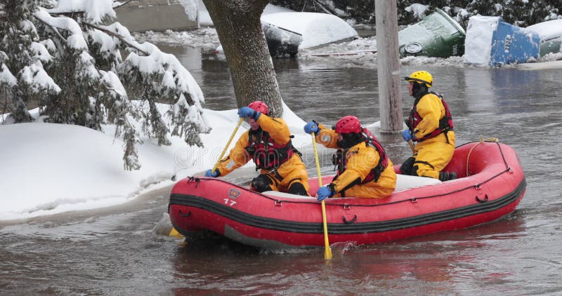 Bomberos en bote de salvamento inflable en la calle inundada