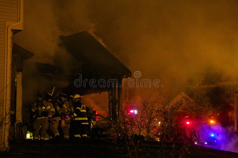 Bomberos que se rompen en una casa ardiente imagen de archivo libre de regalías Bomberos que se rompen en una casa ardiente imagen de archivo libre de regalías