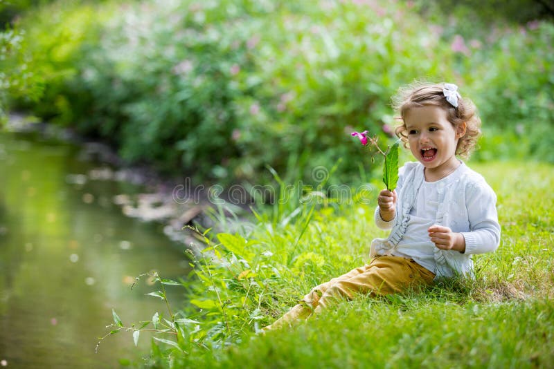 Bonbon, glückliches kleines Mädchen, das auf Gras sitzt lizenzfreie stockfotos Bonbon, glückliches kleines Mädchen, das auf Gras sitzt lizenzfreie stockfotos