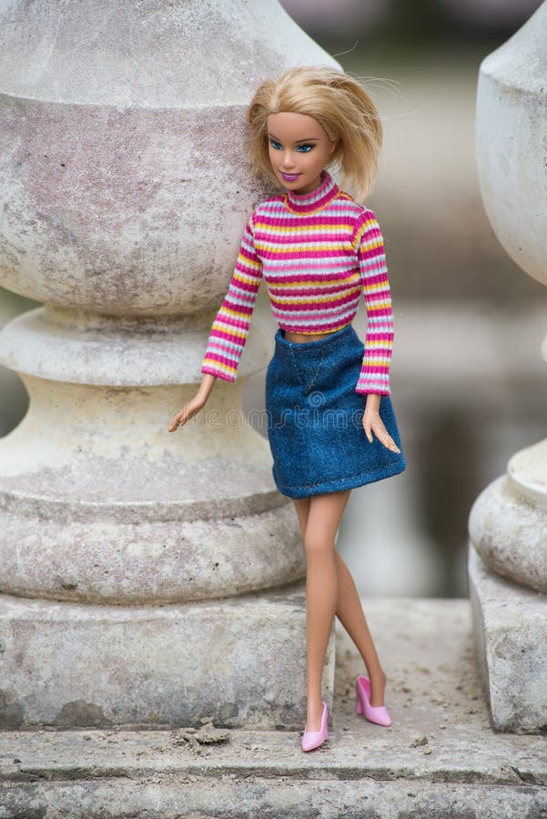 Boneca De Barbie Loira Usando Saia De Jeans Azul E Topo Colorido Em Um  Jardim Público Imagem de Stock Editorial - Imagem de roupa, boneca:  212379739