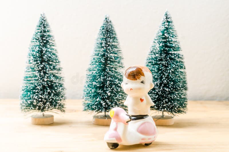 Boneca e velomotor do bebê com fundo das árvores dos chrismas fotos de stock Boneca e velomotor do bebê com fundo das árvores dos chrismas fotos de stock