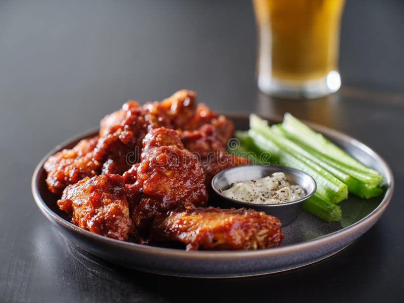 Boneless bbq chicken wings with beer glass in background. Close up