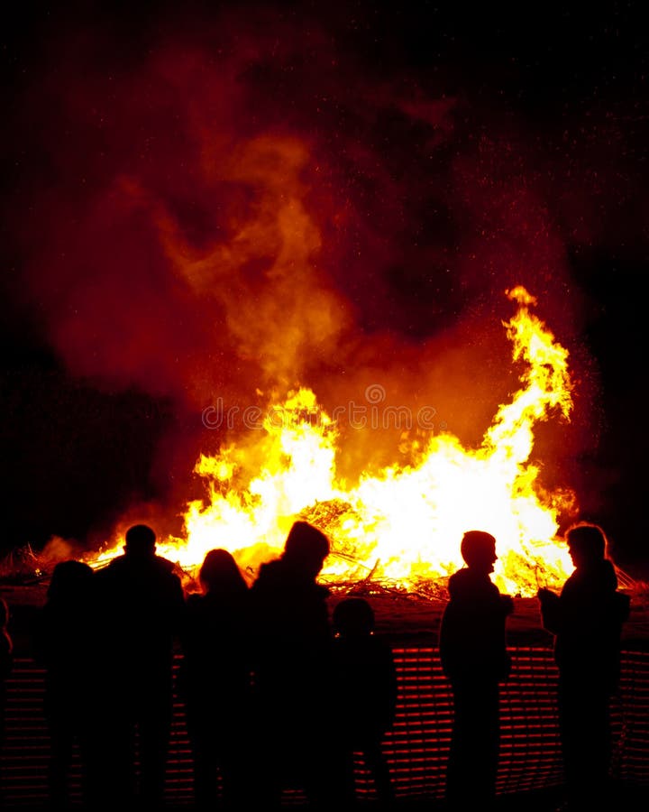 Sagome di persone intorno al fuoco nella notte dei falò.