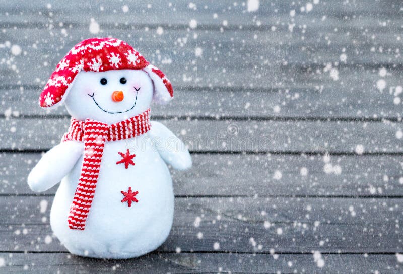 Bonhomme de neige gai et drôle dans un chapeau rouge et une écharpe rouge sur un fond en bois gris Texture en baisse de neige images libres de droits Bonhomme de neige gai et drôle dans un chapeau rouge et une écharpe rouge sur un fond en bois gris Texture en baisse de neige images libres de droits