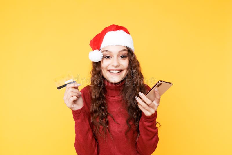 Bonita mujer de Navidad con teléfono y tarjeta de crédito aislada fotografía de archivo libre de regalías Bonita mujer de Navidad con teléfono y tarjeta de crédito aislada fotografía de archivo libre de regalías