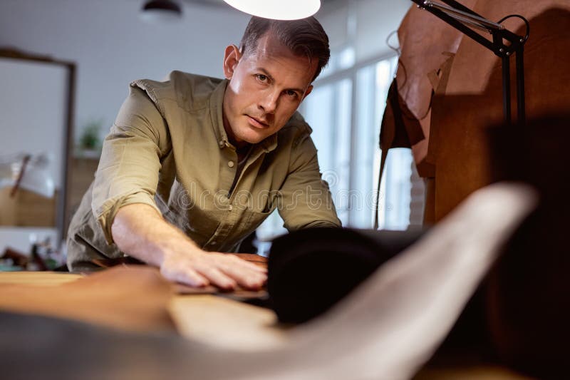 handsome tailor with hands, palms on the material looks at camera, close up cropped portrait. handsome tailor with hands, palms on the material looks at camera, close up cropped portrait.