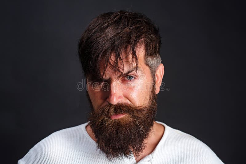 Handsome bearded man in white t-shirt with stylish hair on black. Guy with beard and modern hairstyle in the studio. Handsome bearded man in white t-shirt with stylish hair on black. Guy with beard and modern hairstyle in the studio