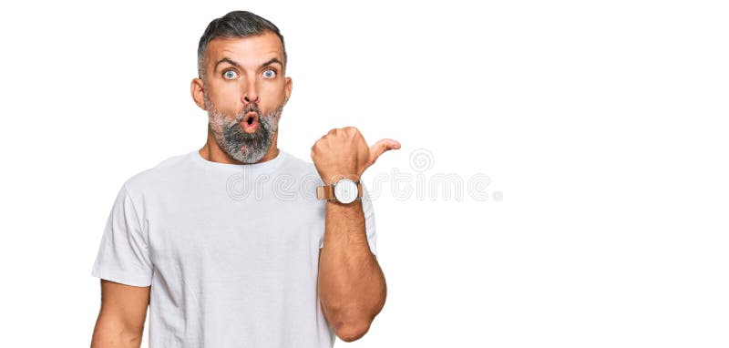 Middle age handsome man wearing casual white tshirt surprised pointing with hand finger to the side, open mouth amazed expression. Middle age handsome man wearing casual white tshirt surprised pointing with hand finger to the side, open mouth amazed expression
