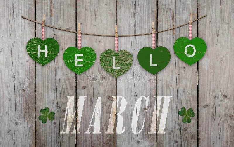 Hello March written on hanging green hearts and weathered wooden background, with clover. Hello March written on hanging green hearts and weathered wooden background, with clover