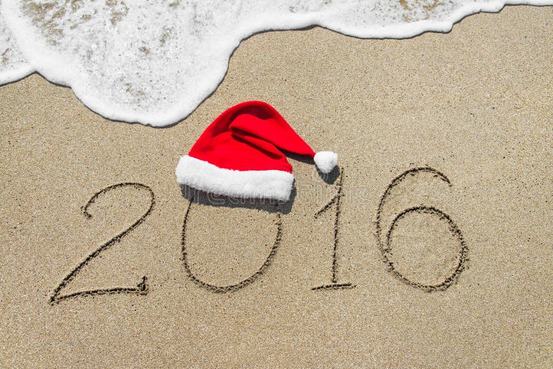 Happy new year 2016 with christmas hat on sandy beach with wave - holiday concept. Happy new year 2016 with christmas hat on sandy beach with wave - holiday concept