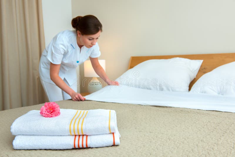 Hotel room service. Young maid changing bedclothes in a room. Hotel room service. Young maid changing bedclothes in a room