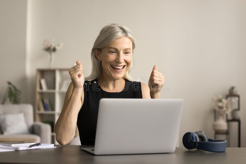 Bonne femme senior mature joyeuse regardant l'écran d'ordinateur portable image stock