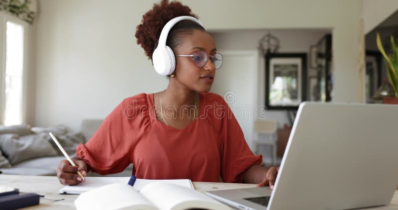 Bonne étudiante africaine en écouteurs regardant une conférence vidéo banque de vidéos