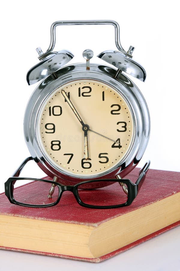 Book with alarm clock and eyeglasses