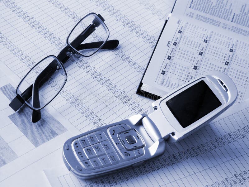 Daily book, glasses, phone on financial figures.