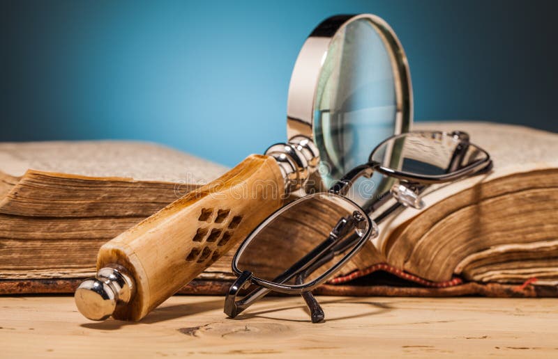 Book magnifying glass and glasses on wooden table stock images Book magnifying glass and glasses on wooden table stock images