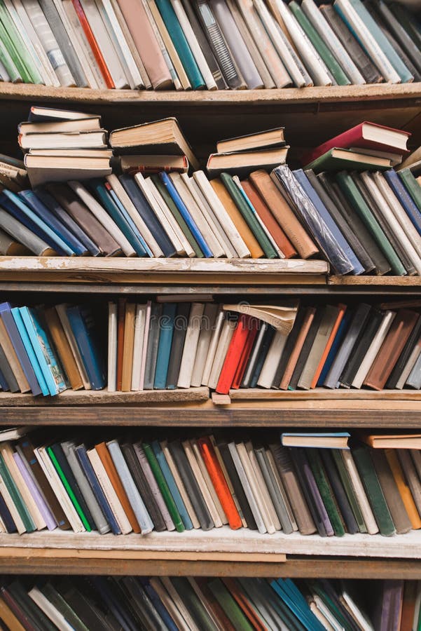 Book shelf with old books. Vertical background of a shelf with books. Old atmospheric library