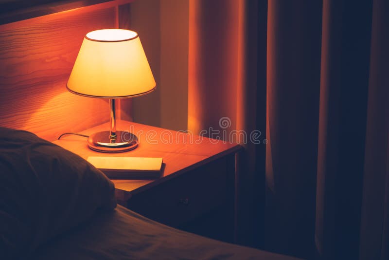 Book and vintage lamp on night table in hotel room