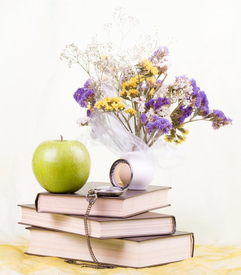 Books, antique clock and flowers