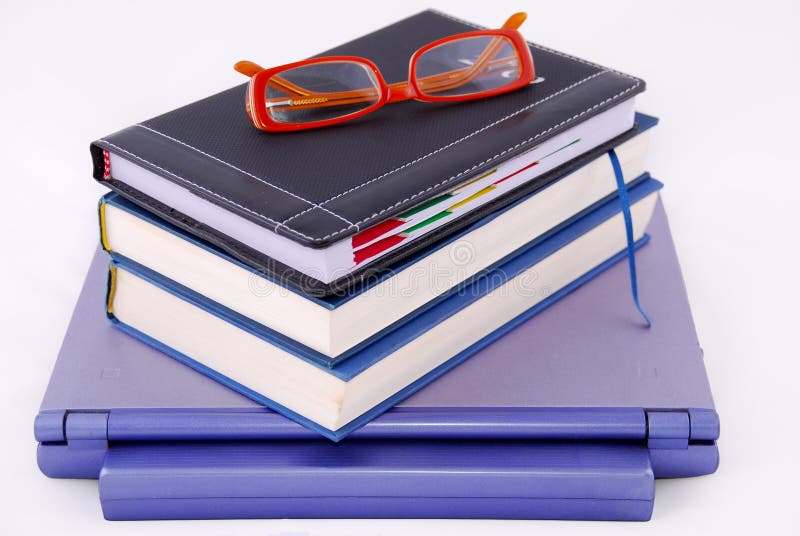 Books and glasses on top of laptop