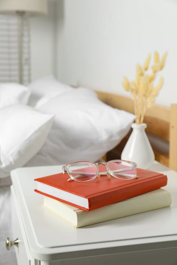 Books and Glasses on White Wooden Bedside Table in Bedroom, Space for