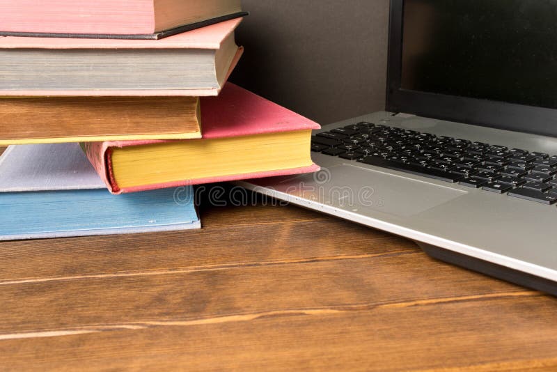 Books and laptop on wooden table. The concept of learning from b