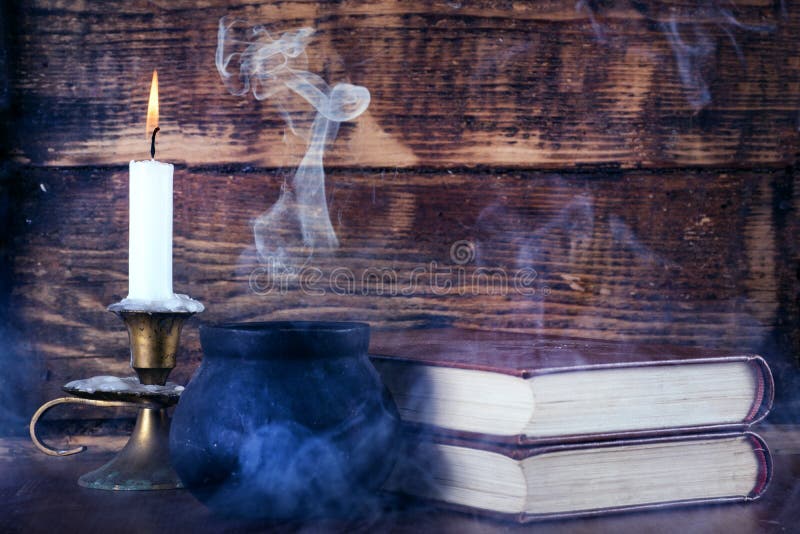 Old books of magic and witch pot with smoke and candle