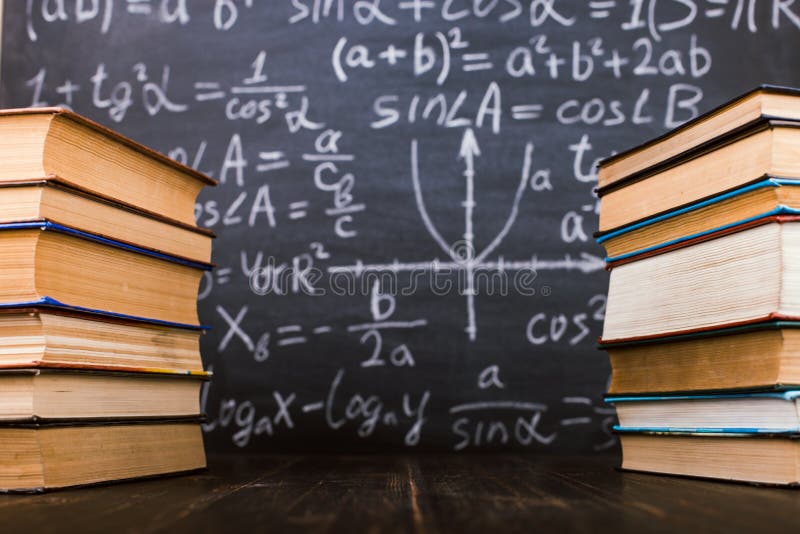 Books on a wooden table, against the background of a chalk board with formulas. Teacher's day concept and back to school royalty free stock photo Books on a wooden table, against the background of a chalk board with formulas. Teacher's day concept and back to school royalty free stock photo
