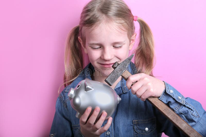 Boos grappig jong meisje met zilveren spaarvarken en hamer op roze achtergrond Sparen geldconcept stock afbeelding Boos grappig jong meisje met zilveren spaarvarken en hamer op roze achtergrond Sparen geldconcept stock afbeelding