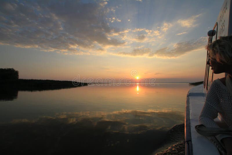 Bootfahrt der jungen Frau bei Sonnenuntergang auf dem Donau-Delta