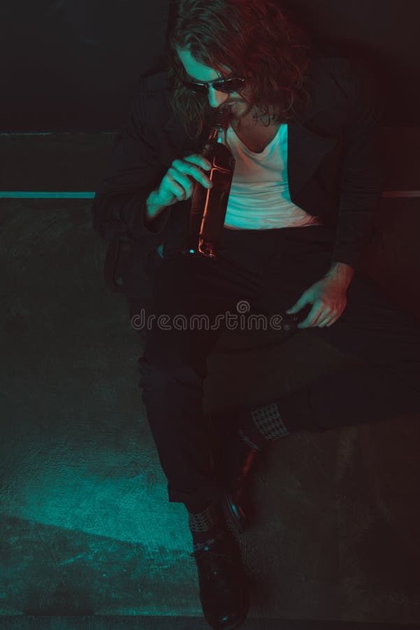 Boozer in Sunglasses Drinking Alcohol from Bottle while Sitting on the