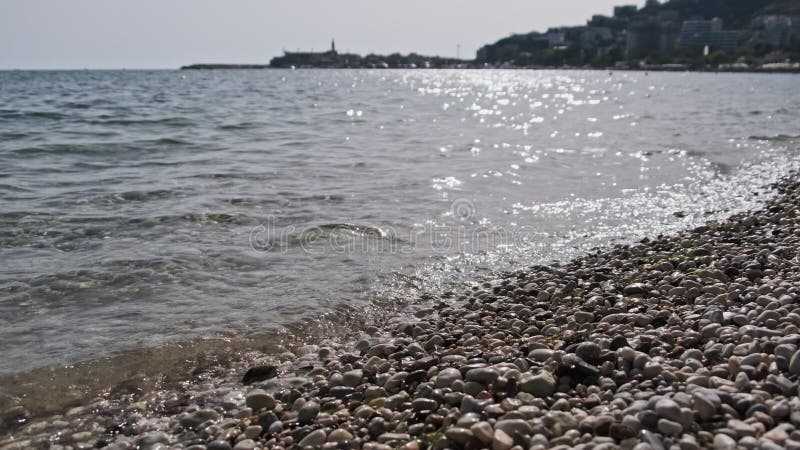Bord d'eau calme sur une plage de galets par beau temps