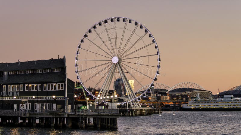 A harbor view of the picturesque Seattle Eye in the evening as the sunsets showcasing the historic buildings, ferry and stadium. A harbor view of the picturesque Seattle Eye in the evening as the sunsets showcasing the historic buildings, ferry and stadium