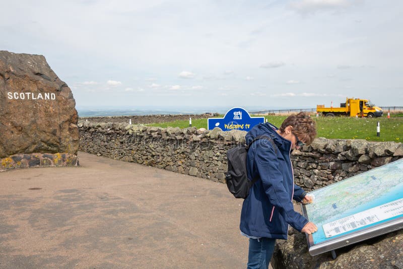 Border between England and Scotland with rock and reading woman stock photos Border between England and Scotland with rock and reading woman stock photos