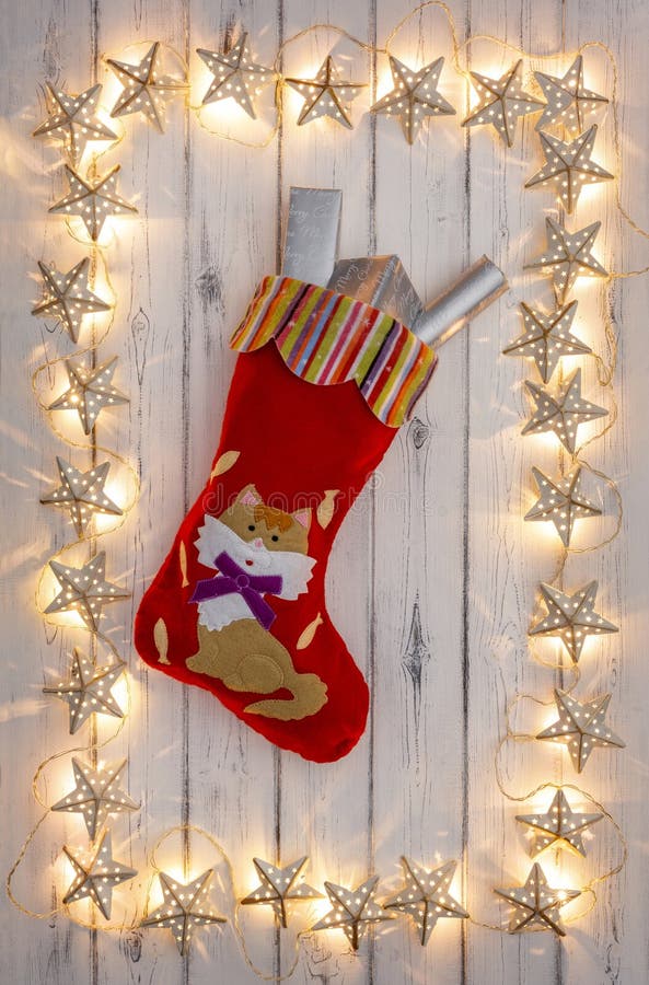 A border of golden star christmas lights, with a kittens christmas stocking and presents, on a destressed woodern background stock photo A border of golden star christmas lights, with a kittens christmas stocking and presents, on a destressed woodern background stock photo