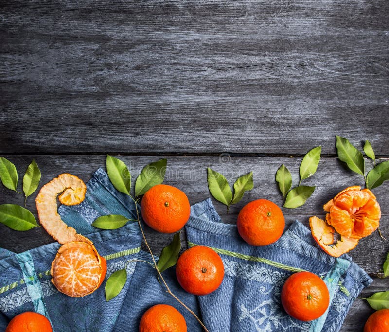 Border of mandarins with leaves on blue rustic wooden background