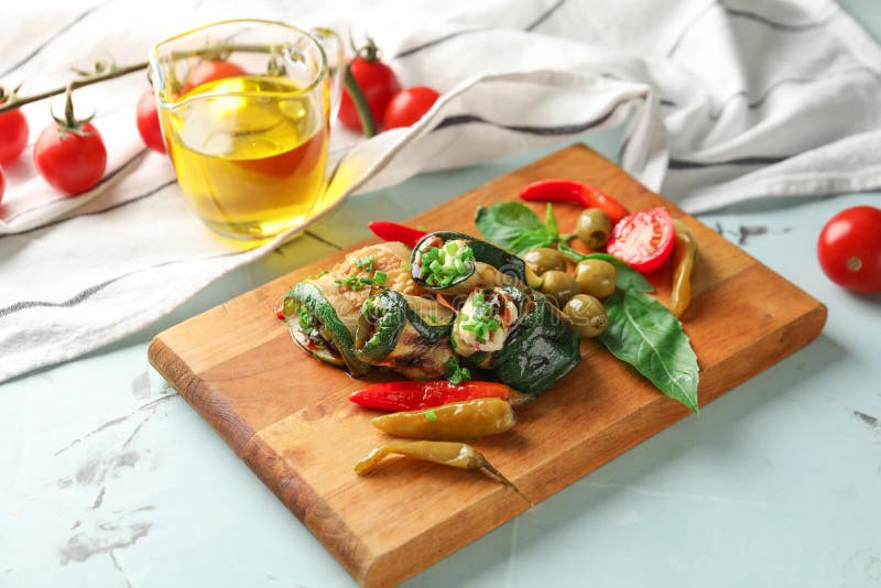 Bordo con i rotoli e le verdure saporiti dello zucchini sulla tavola leggera fotografie stock libere da diritti Bordo con i rotoli e le verdure saporiti dello zucchini sulla tavola leggera fotografie stock libere da diritti