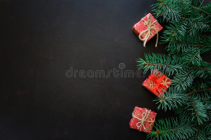 Bordo di natale Rami di albero dell'abete con i contenitori di regalo su fondo di legno scuro immagine stock libera da diritti Bordo di natale Rami di albero dell'abete con i contenitori di regalo su fondo di legno scuro immagine stock libera da diritti