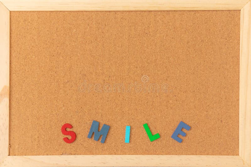 Bordo marrone normale classico del sughero con la lettera variopinta di legno di SORRISO in basso del telaio fotografie stock libere da diritti Bordo marrone normale classico del sughero con la lettera variopinta di legno di SORRISO in basso del telaio fotografie stock libere da diritti