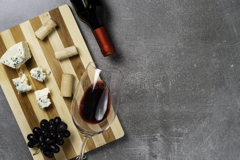 Bordo a strisce con formaggio e vetro con vino su fondo concreto Copi lo spazio immagine stock