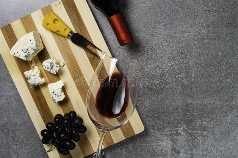Bordo a strisce con formaggio e vetro con vino su fondo concreto Copi lo spazio fotografie stock libere da diritti