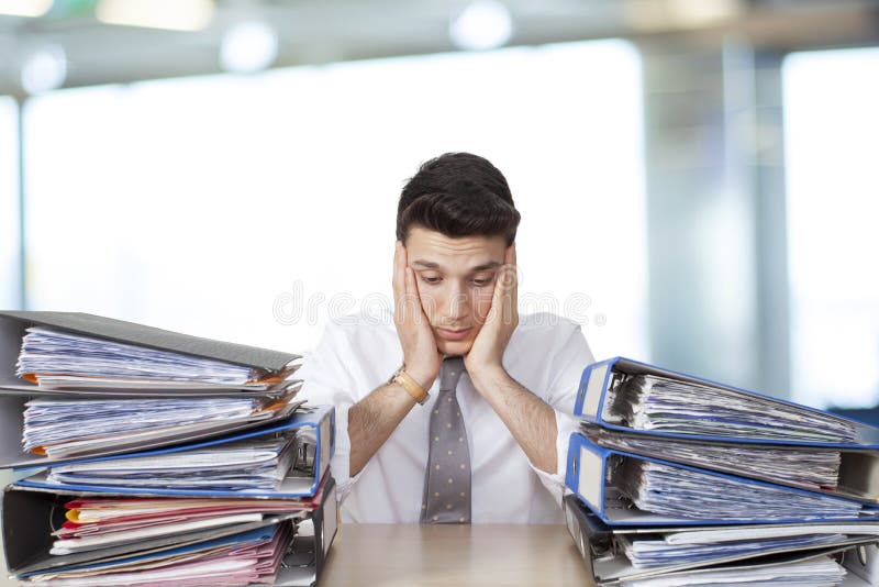Bored businessman in office with files stock images