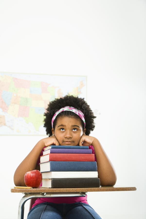 African American girl sitting in school desk with large stack of books looking bored. Boring kid white stock images, royalty-free photos and pictures